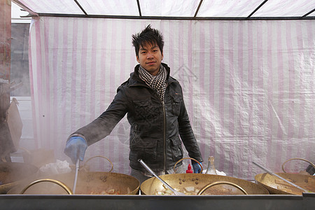 一名亚洲青年男子在街头食品摊做饭的肖像图片