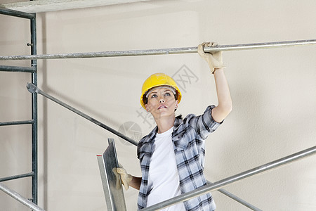 中年女性建筑师站在建筑工地脚手架下抬头看图片