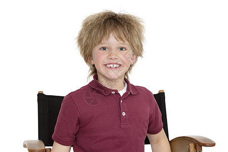 一个快乐的学校男孩的肖像 坐在导演的椅子上 白背景图片