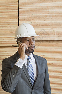非裔美国男性工程师在电话中打来电话 背着堆叠的木木板图片