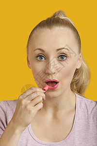 美丽的年轻女人的肖像 用黄底涂口红画黄色背景金发女性影棚保养头发嘴唇特写美容成年化妆品图片