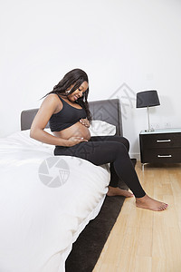 年轻孕妇在床上摸肚子的年青孕妇图片