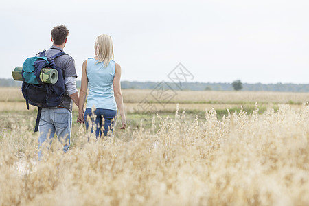 年轻徒步旅行夫妇在田野中行走的近视图片