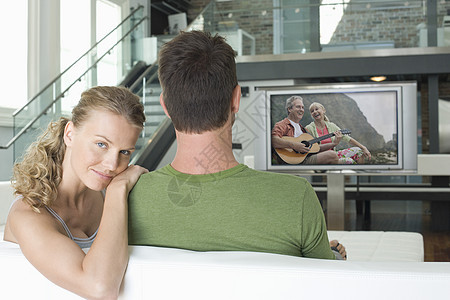 在客厅电视上观看电影的男男女女白人年轻女子的肖像成人头肩两个人成年闲暇男士屏幕沙发娱乐休闲图片