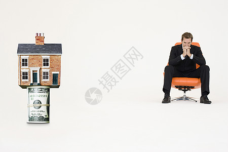 房顶上挂着一卷法案 被收买的商务人士坐在椅子上代表昂贵地产屋主经济影棚产权男性焦虑中年纸币男士沉思图片