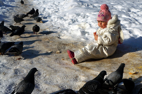 身着白甘巴尼松的两岁女孩坐在雪地上图片