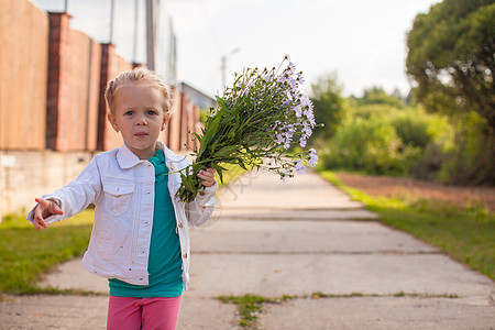 小女孩带着鲜花在户外散步图片