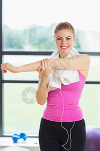 在健身房用毛巾围着颈部 伸手的妇女身体金发女郎热身活动俱乐部健身女性听力瑜伽双手图片