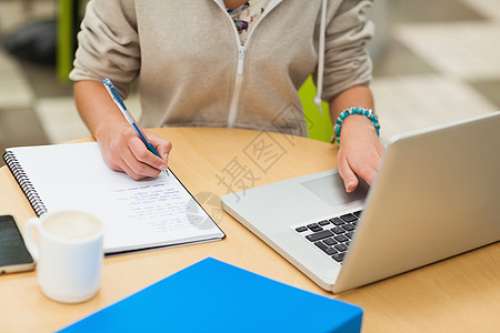 女学生用笔记本电脑做家庭作业的中间部分图片