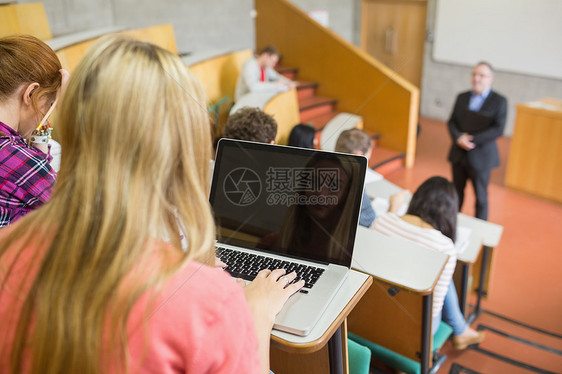 女性与学生和教师在教室使用笔记本电脑金发老师教学学习班级金发女郎知识混血演讲桌子图片