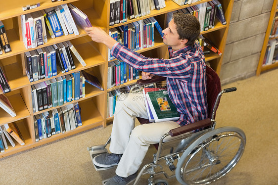 在图书馆里挑选书本的轮椅男图片