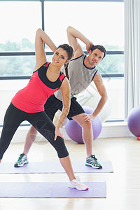 两个人在瑜伽课上练体力锻炼双手身体俱乐部活动训练健身室班级运动垫男性女士图片