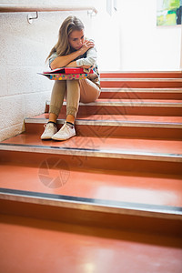 坐在楼梯上的学生心烦悲哀教育女性大厅寂寞愁云图书笔记本脚步红发图片