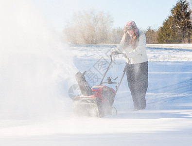 年轻妇女与吹雪者清扫车天气打扫驾驶人行道工作车道暴风雪季节机械住宅图片
