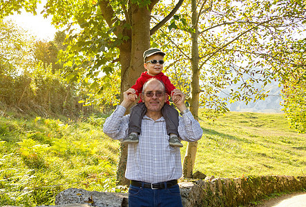 爷爷把孙子抱在外祖父的肩膀上快乐乐趣幸福孩子成人家庭闲暇老年帽子祖父母图片