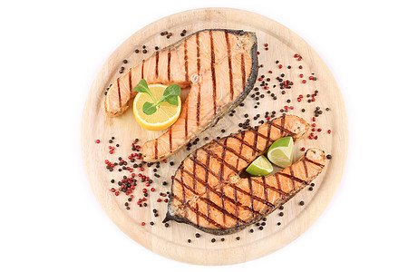 两条鲑鱼牛排在盘子上柠檬油炸橙子红色粉色鱼片木头蔬菜黑色食谱图片
