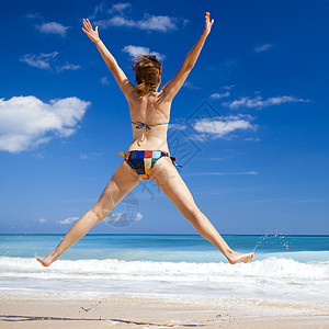 女人在海滩上跳跃棕褐色闲暇游泳衣跑步天堂热带乐趣女性旅行假期图片