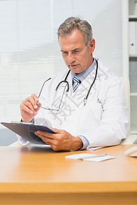 集中成熟的医生 坐在桌子前用剪贴板图片