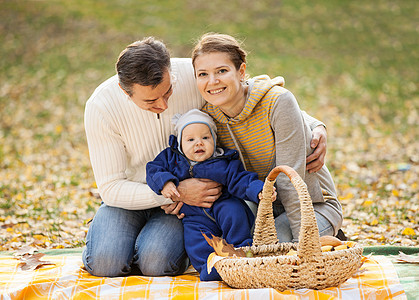 年轻夫妇和小男孩在秋天野餐图片