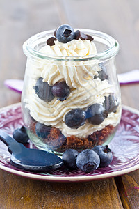 配有新鲜蓝莓的多层甜点水果奶油紫色冰冻勺子巧克力琐事玻璃盘子蛋糕图片