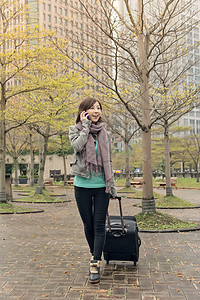 街头旅行妇女手机微笑乘客女士技术公园游客手提箱魅力行李背景图片