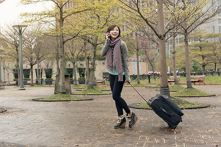 街头旅行妇女乘客手机公园技术微笑行李女性电话手提箱魅力图片