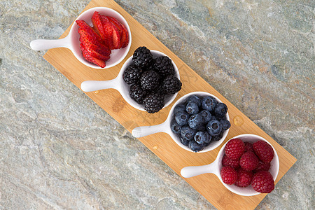 木板上草莓中间方排列的新鲜浆果磁盘背景