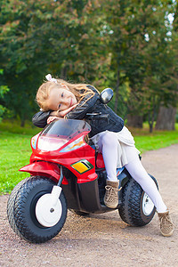 美丽的小女孩在玩具摩托车上玩得开心的图片