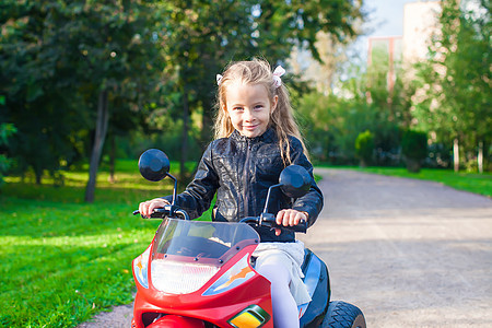 可爱的小女孩骑着玩具摩托车喜悦幼儿园速度自行车游戏童年乐趣微笑女孩运动图片