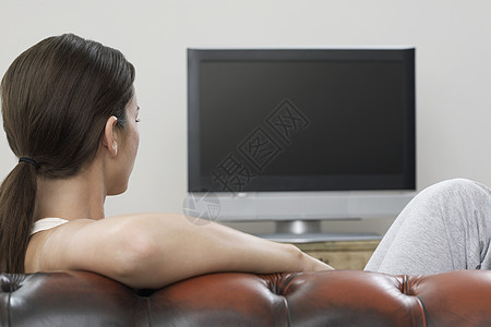 在沙发上看平板屏幕电视的年轻女青年图片