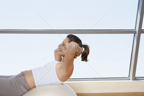 在健身房运动舞会上做坐起坐的妇女窗户棕色一人活力中年女性极限健身头发斗争图片