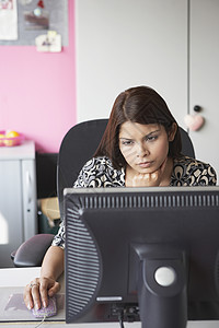 办公室工作人员使用计算机坐在办公桌高视台后面的中年女士一人设备长发专注成人女性服装商业图片