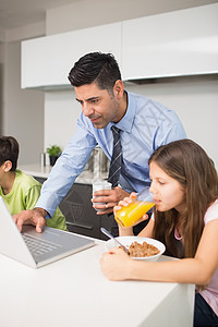 父亲使用笔记本电脑 孩子在厨房吃早餐儿子杯子女儿餐桌团结童年房子技术公寓兄弟姐妹图片