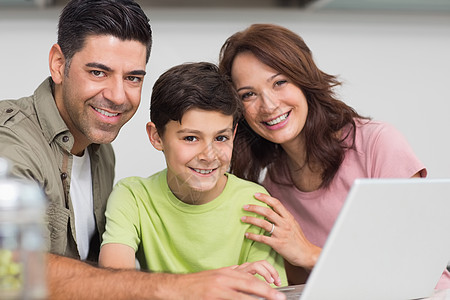 妈妈的微笑使用笔记本电脑与儿子一起微笑的一对夫妇成人孩子房子父母技术男性父亲公寓女士男生背景