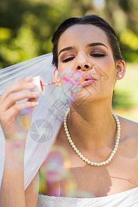 美丽的新娘在公园吹肥皂泡图片