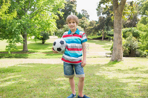 一个微笑的男孩在公园玩球的肖像图片