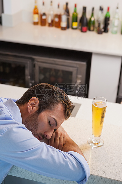 醉酒商务人士睡在啤酒杯边图片