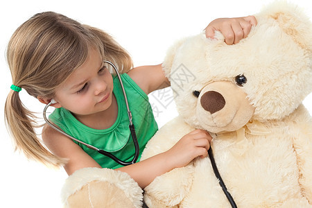 可爱的小女孩玩医生 用她的泰迪熊图片