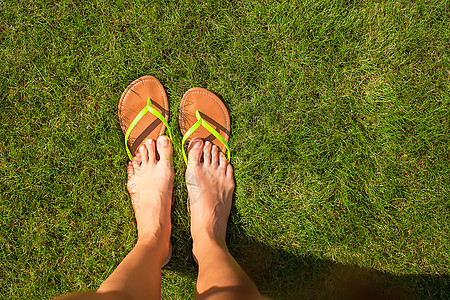 在绿草上用拖鞋紧紧女人的腿配饰衣服字拖阳光旅行装饰品黄色绿色娱乐热带图片