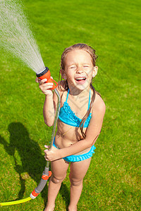 快乐可爱的小女孩 从水管里倒水 笑着金发乐趣喜悦灌溉女儿花园女孩孩子运动液体图片