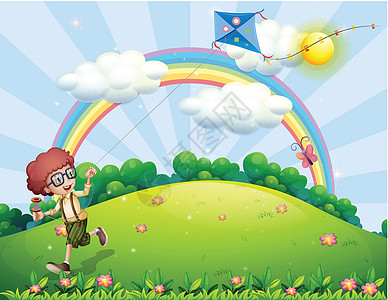 一个男孩在山顶用彩虹 玩风筝图片