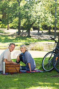 夫妻在公园享受野餐闲暇男性自行车烧瓶成人热水瓶亲热女性便服空闲图片