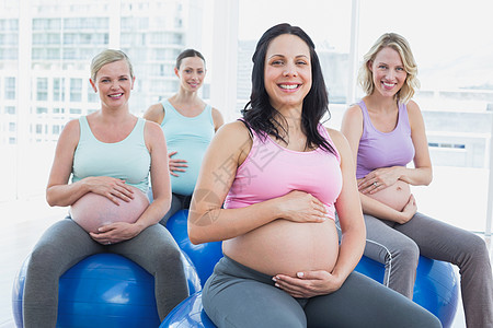 坐在运动球场上微笑的怀孕妇女图片