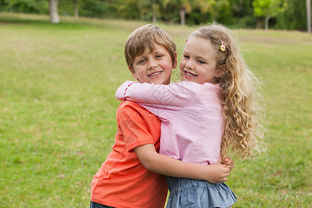 两个微笑的孩子 拥抱在公园图片
