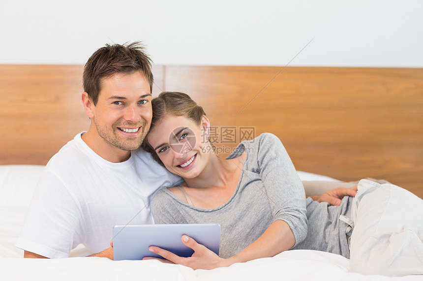 使用平板电脑在床上快乐的情侣幸福团结药片家庭房子闲暇住所感情拥抱羽绒被图片