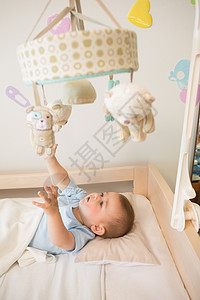 躺在婴儿床的婴儿宝宝男孩玩手机游戏蓝色手指房子住所服装新生活男性双手男生家庭图片