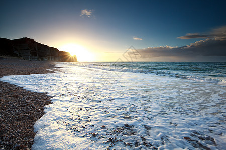 日落时岩石海滩上的海浪图片