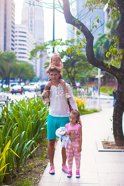 年轻父亲在大城市户外与小女孩一起走着图片