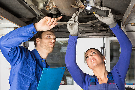 在液压坡道修理一辆汽车的机械机作坊技术技术员女性维修工人男人引擎服务男性图片