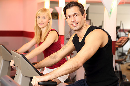 迷人的女人和男人在健身房骑自行车有氧运动身体成年人运动运动服训练女性健身家庭俱乐部图片